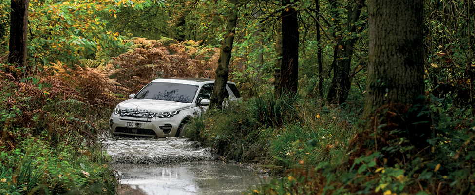 Land Rover Discovery Sport wading through water on a flooded trail.
