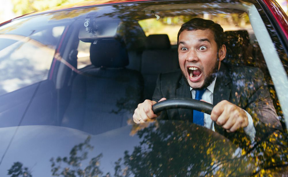 Furious driver gesticulates with open hand on white car. Desperate young  man with sunglasses driving with anger. Upset, aggressive, impatient, bad  manners concepts. Cold blue effect on sunny day Stock Photo